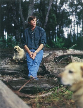 Tim McCartney at home on a log with dogs, 1998