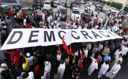 Arab protestors carrying a sign reading ‘Democracy’