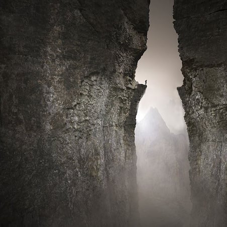 Image of person standing on edge of terrible chasm in mountains