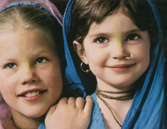 Two angelic looking girls in mid-childhood wearing traditional headress from a Hare Krishna commune in the United States.