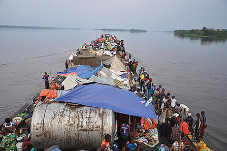 A large barge on the Congo River in Africa carrying a mass of people in makeshift living conditions