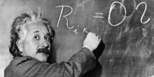 Albert Einstein writing a maths formula on a chalk board