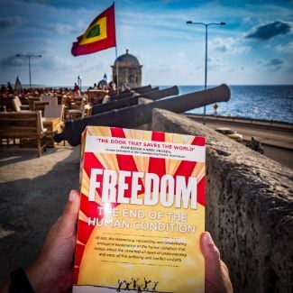 FREEDOM frente a la bandera colombiana y cañones - Recomendaciones del World Transformation Movement