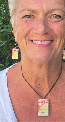 Person wearing FREEDOM pendant and earrings