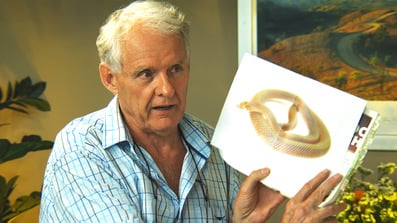 Jeremy Griffith holding up a book with an image of a snake coiled up explaining the snake phobia analogy