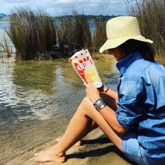 Woman reading FREEDOM at Kai Iwi Lakes