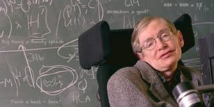 Stephen Hawking in wheel-chair in front of chalk board