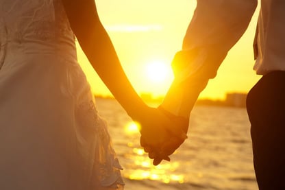 Man and woman holding hands with sunset background
