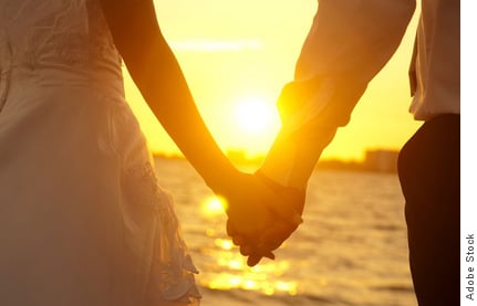Man and woman holding hands with sunset background