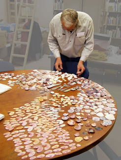 Jeremy Griffith sorting colourful shells on a table.