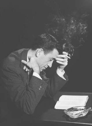 J.D. Salinger sitting at a desk smoking while reading a book