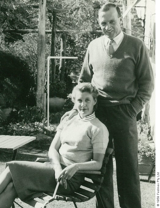 Black and white portrait of Norman Griffith standing with his hand on the shoulder of Jill Griffith sitting at a garden table