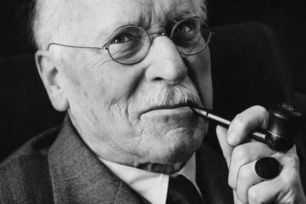 Black and white portrait photograph of Carl Jung smoking a tobacco pipe