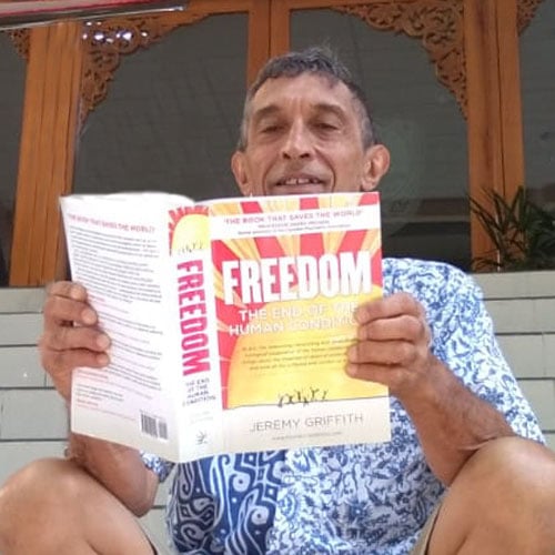 Michael sitting on steps reading Freedom - available from the World Transformation Movement