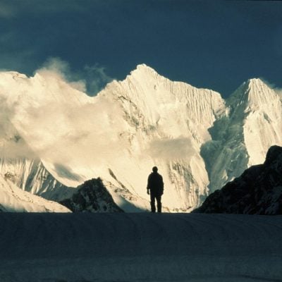 Person standing in front of a snow covered mountains with some low cloud in Pakistan