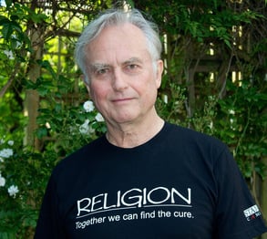 Richard Dawkins wearing a black t-shirt with the slogan ‘RELIGION - Together we can find the cure’