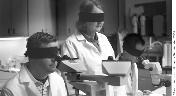 Scientists wearing blindfolds while looking into microscopes in a laboratory