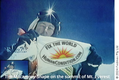 Tim Macartney-Snape holds the FHA’s (as the WTM was then known) flag aloft on the summit of Mount Everest. This version has replaced the FHA's logo with the WTM Fix The World logo.