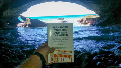 TYL book by Jeremy Griffith in Waenhuiskrans Cave with the cave opening to the ocean in the background
