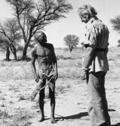 Sir Laurens van der Post standing talking to a Bushman