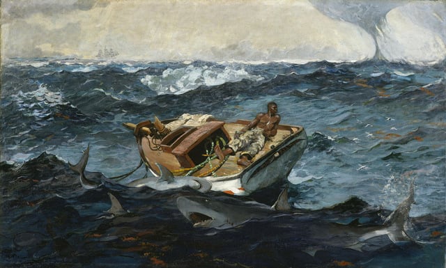 A man lies alone on the deck of a disabled boat in stormy seas and circled by menacing looking sharks