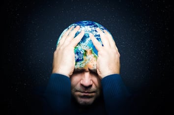 Grimacing man holding his head (a globe of the planet) in his hands.
