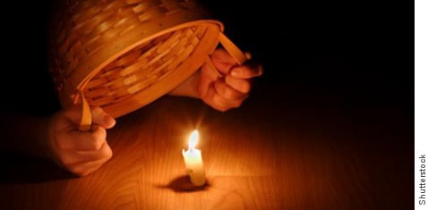 Person putting a basket over a candle