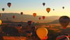 Many hot air balloons aloft at dawn