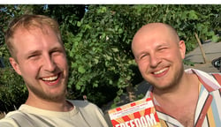 Two young men smiling holding a copy of the book titled FREEDOM by Jeremy Griffith