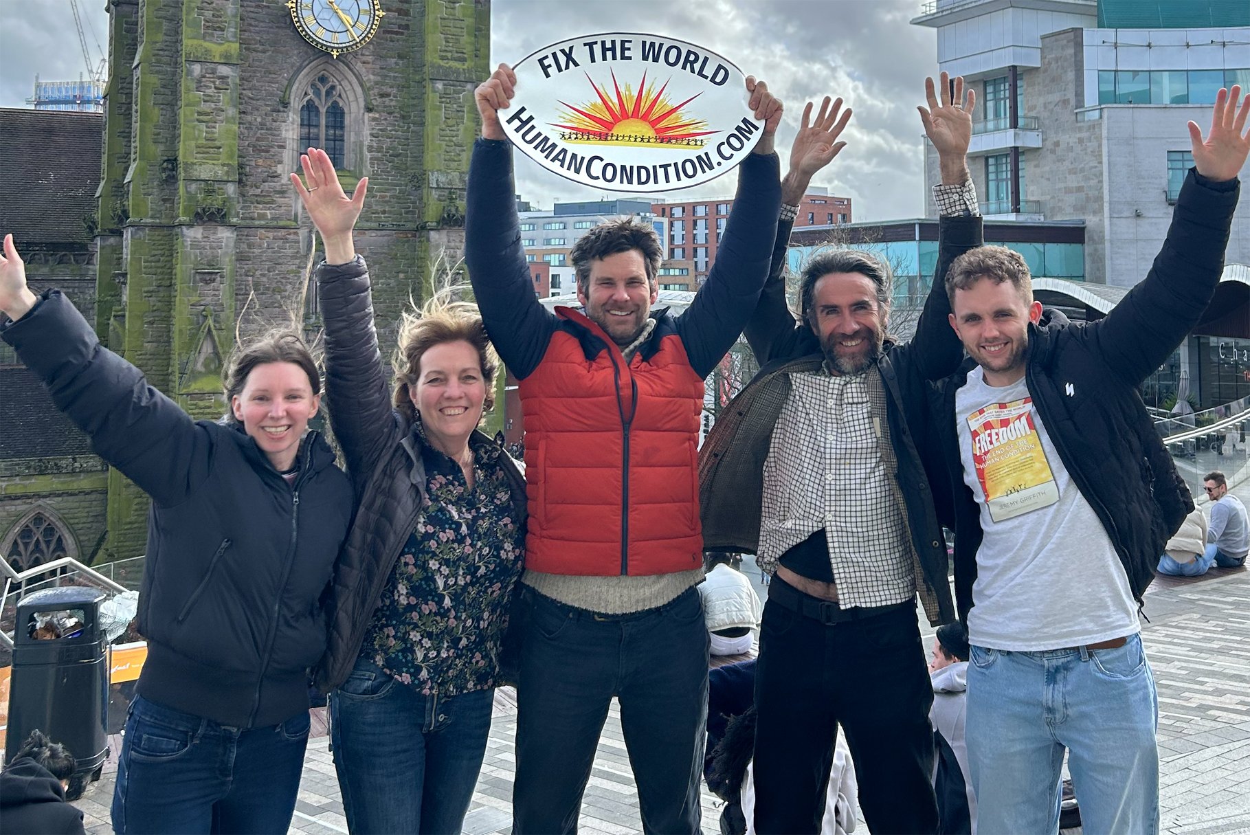 Jack and fellow founders of WTM Centres in the United Kingdom with arms in the air holding the Fix The World banner