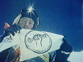 Tim on the summit of Mt Everest in 1990, with the flag of the FHA, which was  renamed the World Transformation Movement in 2011