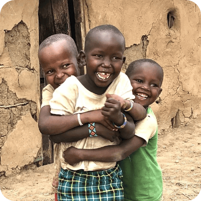 3 young African children laughing and hugging