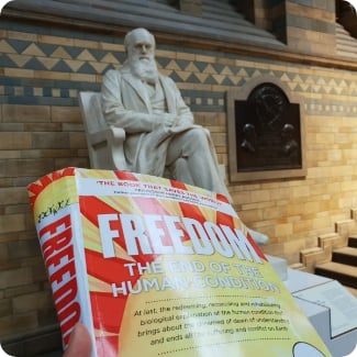 The book FREEDOM in front of statue of Charles Darwin