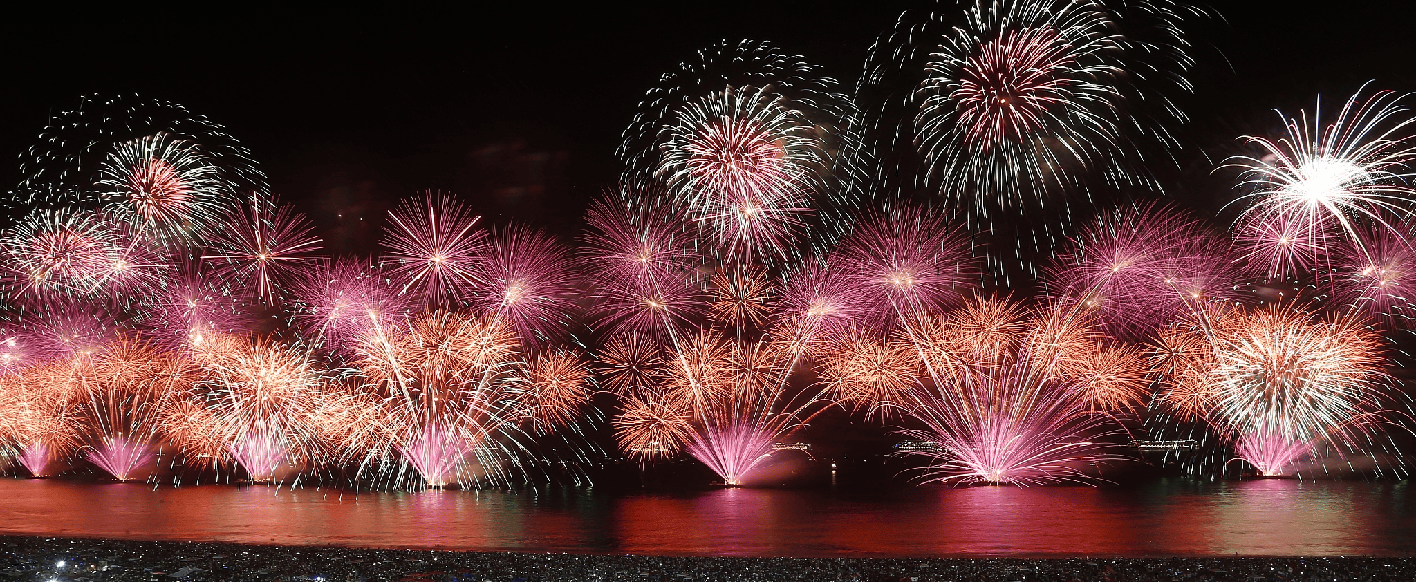 Spectacular firework display lighting up the night sky with pink, orange blue and silver